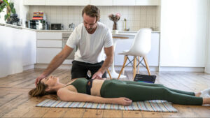 Practitioner providing personalized physical therapy or wellness assessment to a patient during an at-home spine, posture, or rehabilitation session.