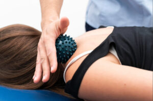 Therapist performing targeted neck and upper back muscle therapy with a massage ball to relieve cervical tension and support spine rehabilitation.