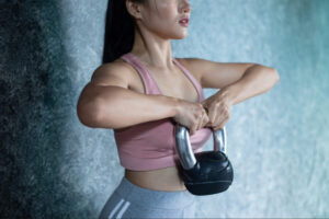 Woman performing kettlebell strength training exercise to build upper body stability, muscular endurance, and overall fitness performance.