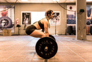 Woman performing a deadlift with proper form in a gym, demonstrating strength training, athletic conditioning, and musculoskeletal injury prevention.