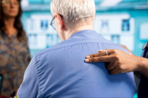 Healthcare professional assessing an older adult’s upper back and shoulder area during a clinical spine or musculoskeletal evaluation.
