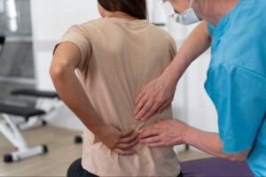 Healthcare provider examining a patient’s lower back during a clinical sciatica or spine evaluation to assess pain, mobility, and treatment needs.