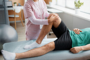 Physical therapist assisting a patient with knee mobility exercises during rehabilitation and recovery after knee arthroplasty surgery.