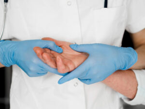 Healthcare professional examining a patient’s hand and wrist during a pre-operative evaluation for carpal tunnel release surgery.