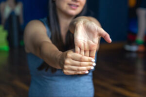Woman performing wrist and hand stretching exercises during rehabilitation and physical therapy recovery after carpal tunnel release surgery.