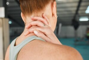 Person experiencing neck pain and stiffness, common symptoms that may lead to cervical fusion surgery evaluation