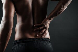 Person experiencing severe lower back pain during recovery after microdiscectomy surgery