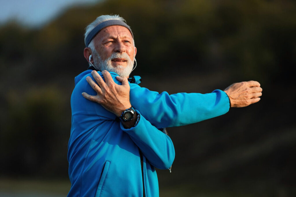 Active senior stretching his shoulder and neck during rehabilitation after cervical fusion surgery